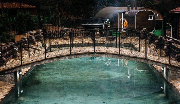 Бассейн с водой из горной реки у кованого мостика
